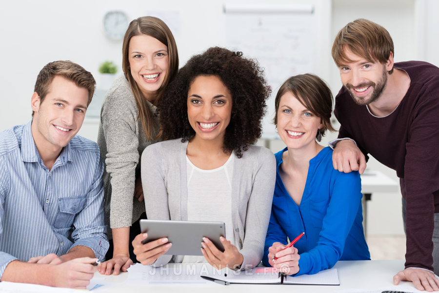 Successful motivated multiethnic business team posing grouped around an attractive African American woman looking at the camera with beaming friendly smiles